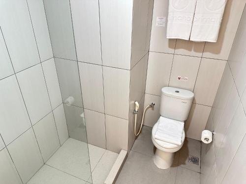 a small bathroom with a toilet and a shower at d'primahotel Jemursari Surabaya in Surabaya