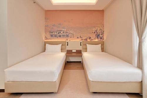 two beds in a room with a painting on the wall at Cititel Express Ipoh in Ipoh