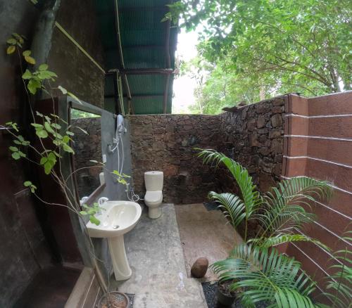 La salle de bains est pourvue d'un lavabo et d'un mur en pierre. dans l'établissement Coconut Tree House, à Uda Walawe