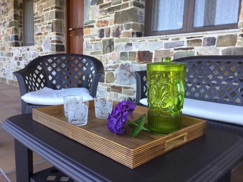 a table with a green vase and flowers on it at El Mirador de los Trobos in Villar de Otero