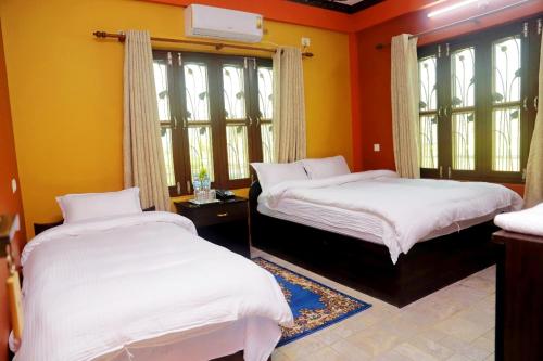 two beds in a room with yellow walls and windows at Hotel Park Treasure in Chitwan