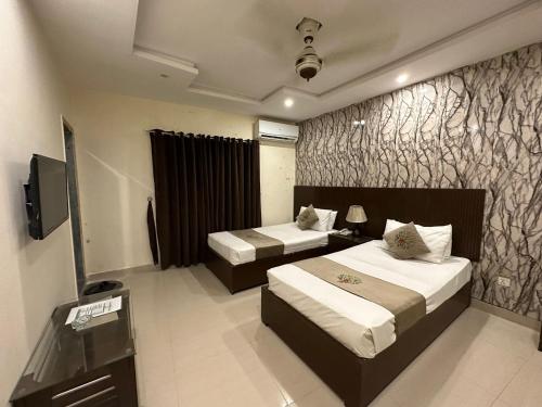 Hotel Green Fort Gulberg في لاهور: غرفة فندقية بسريرين وتلفزيون