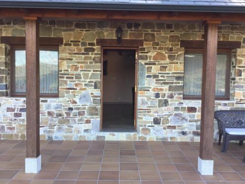 a building with a stone wall and a wooden porch at El Mirador de los Trobos in Villar de Otero