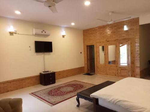 1 dormitorio con 1 cama y TV de pantalla plana en Ghairaat Castles, en Chitral