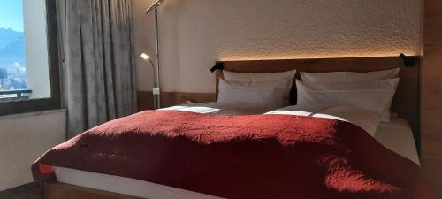 a bedroom with a bed with a red blanket and a window at Berghof Mehlan in Fischen