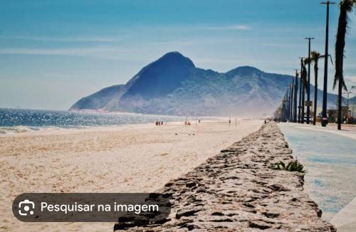 une plage de sable avec des montagnes en arrière-plan dans l'établissement Kitnet dos Alves, à Maricá