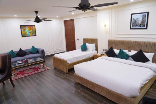 pokój hotelowy z 2 łóżkami i kanapą w obiekcie Elegant Executive Suite w mieście Multan