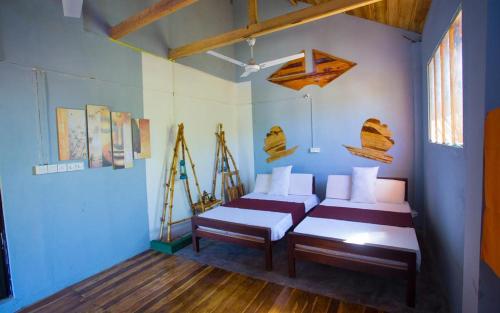 Habitación con 2 camas, paredes azules y suelo de madera. en Neem Forest Guest House & Yoga Meditation Centre, en Batticaloa