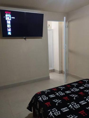 1 dormitorio con TV de pantalla plana en la pared en departamento individual equipado, en Ibarra