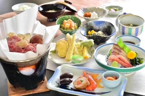 una mesa con muchos platos de comida. en Kumanoyu Hotel, en Yamanouchi