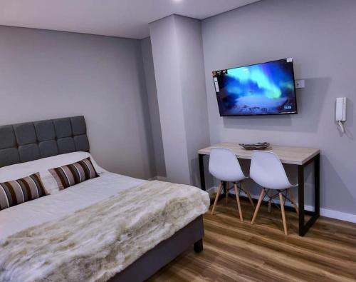 Un dormitorio con una cama y un escritorio con dos sillas. en Céntrico Loft Turístico-Negocios, en Bogotá