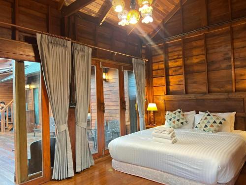 a bedroom with a bed in a room with wooden walls at Bann Rai I Na in Phrae