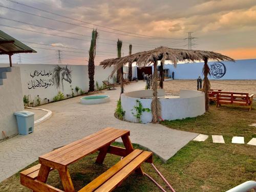 een picknicktafel en een bankje op het strand bij مربط الجازي in Ad Dihāsīyah