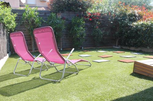 Deux chaises roses assises sur l'herbe dans une cour dans l'établissement Graziosa villetta in residence con piscina a 100 m dalla spiaggia, à Cervione