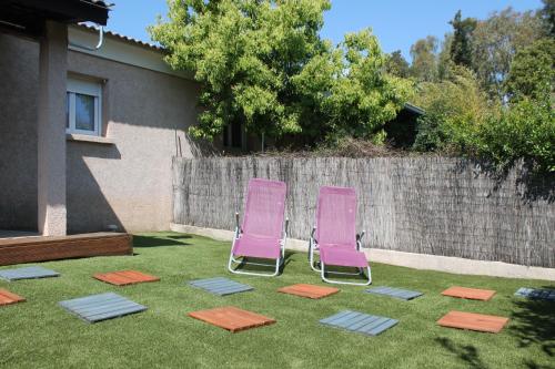 Deux chaises roses assises sur l'herbe dans une cour dans l'établissement Graziosa villetta in residence con piscina a 100 m dalla spiaggia, à Cervione