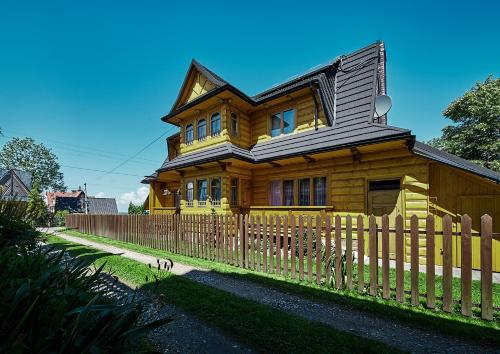 a wooden house with a fence in front of it at Dom Rodzinny in Ząb