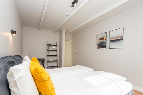 a bedroom with a white bed with yellow pillows at Vaivute Apartments No2 in Darbėnai