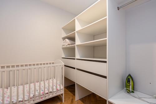 a baby room with white shelves and a crib at Vaivute Apartments No2 in Darbėnai