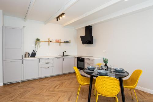 a kitchen with a dining table and yellow chairs at Vaivute Apartments No2 in Darbėnai