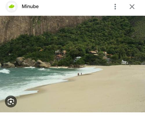 Una foto de una playa con gente caminando por la arena en Kitnet dos Alves en Maricá