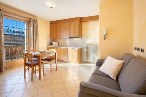ein Wohnzimmer mit einem Sofa und einem Tisch sowie eine Küche in der Unterkunft Al Bait da Marangona in Livigno
