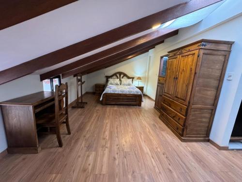 a bedroom with a bed and a desk and a wooden floor at Abis Terraza in Sucre