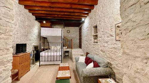 ein Wohnzimmer mit einer Steinmauer mit einem Sofa und einem Kinderbett in der Unterkunft Juliet Suite by TrulyCyprus in Doros