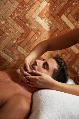 a shirtless man laying in a bath tub at Sofitel Golfe d'Ajaccio Thalassa Sea & Spa in Ajaccio