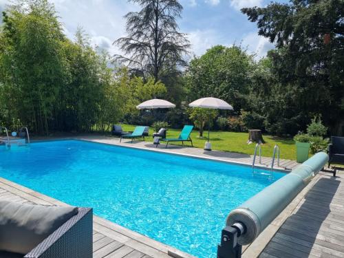 a swimming pool with blue chairs and umbrellas at Villa Géna in Saint-Médard-dʼEyrans