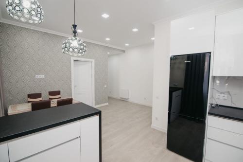 a kitchen with white cabinets and a black counter top at ApartHotel City Centrum in Chişinău