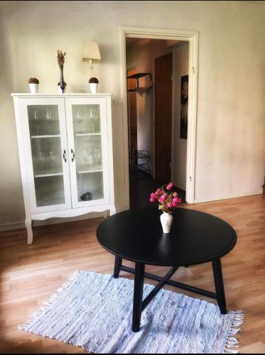 Zimmer mit einem Tisch und einem Schrank mit einer Blumenvase in der Unterkunft Fagersta Apatrtment in Fagersta