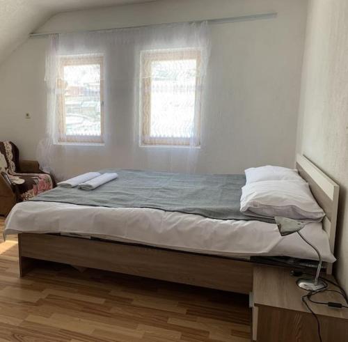 a large bed in a bedroom with two windows at Vejtse House 