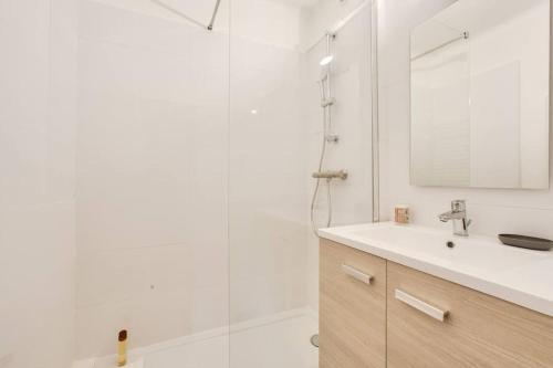 une salle de bain blanche avec un lavabo et une douche dans l'établissement Merville, charmant appartement proche centre-ville, à Lorient