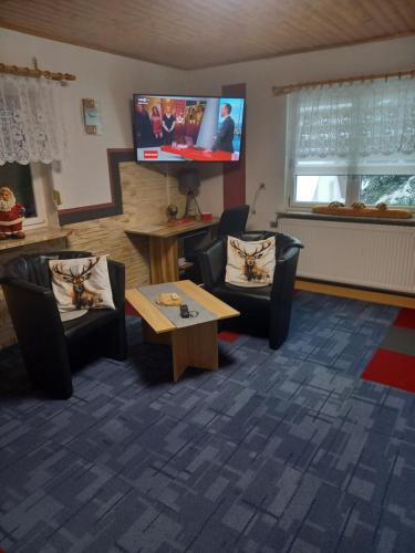 a waiting room with chairs and a tv and a table at Monteur- und Ferienwohnung Waldrauschen in Fehrenbach