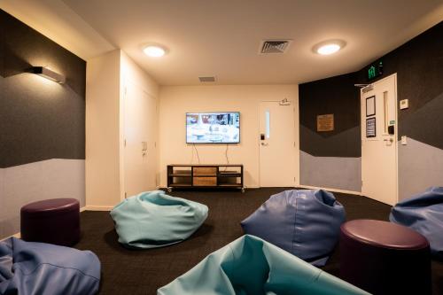 uma sala de espera com cadeiras azuis e uma televisão de ecrã plano em Haka House Lake Tekapo em Lake Tekapo