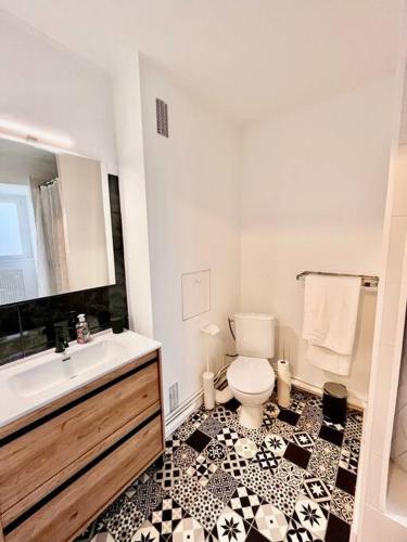 La salle de bains est pourvue de toilettes blanches et de carrelage noir et blanc. dans l'établissement Charmant studio en vieille Ville de Belfort, à Belfort