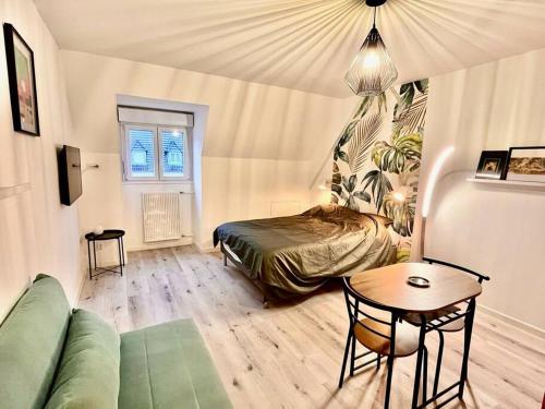 une chambre avec un lit, une table et un canapé dans l'établissement Charmant studio en vieille Ville de Belfort, à Belfort