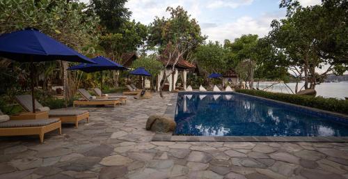 a swimming pool with chairs and umbrellas next to a resort at Plataran Komodo Resort & Spa - CHSE Certified in Labuan Bajo