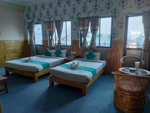 Duas camas num quarto com janelas em Pokhara Hotel Deep Sagar em Pokhara