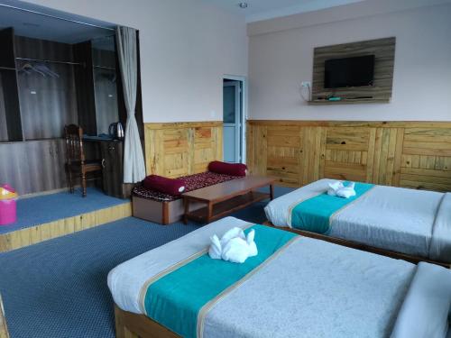 um quarto de hotel com duas camas e uma televisão em Pokhara Hotel Deep Sagar em Pokhara