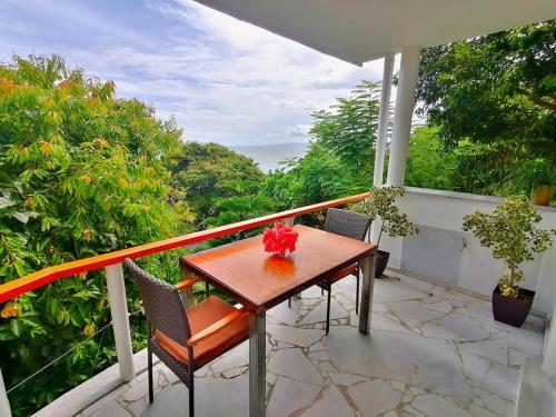 a wooden table and chairs on a balcony with trees at Lonos Circle Ocean View Room in Romblon