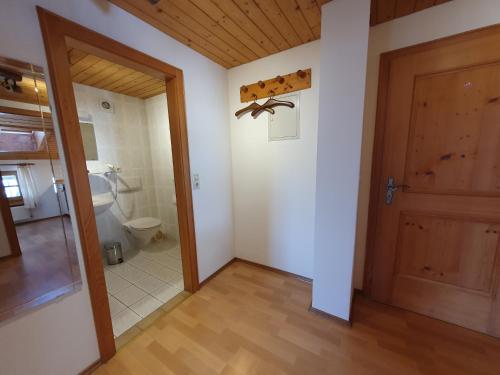 a bathroom with a toilet and a wooden door at Prümbachhof in Schneizlreuth