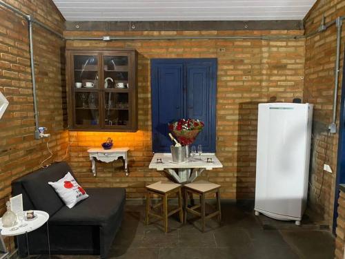 a room with a brick wall with a refrigerator and tables at Refugio do Amor in São João del Rei