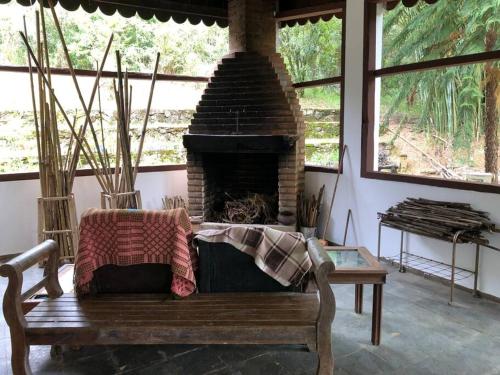 a living room with a fireplace and a wooden bench at Refugio do Amor in São João del Rei