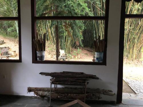 a room with two windows and a table and trees at Refugio do Amor in São João del Rei