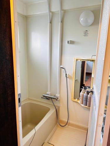 a bathroom with a bath tub and a mirror at 蒼穹 in Asahikawa