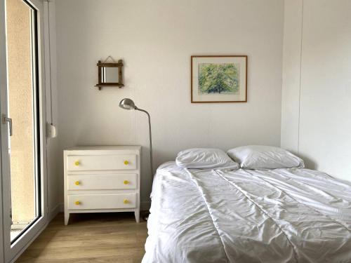 een slaapkamer met een bed, een lamp en een dressoir bij Appartement à 200m de la mer à TREGASTEL PLAGES - Réf 744 in Trégastel