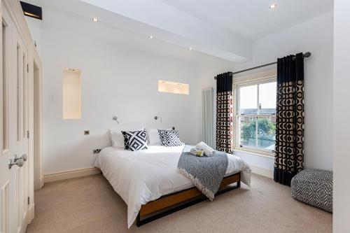 a white bedroom with a bed and a window at Thrushley Cottage in Wakefield - sleeps 7 - with roof terrace 