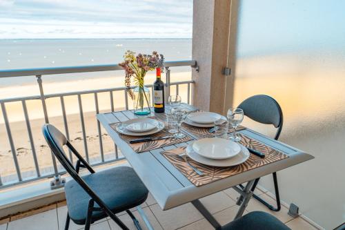- une table avec des assiettes et des verres à vin sur un balcon donnant sur la plage dans l'établissement Vue Bassin - Accès plage, à Arcachon