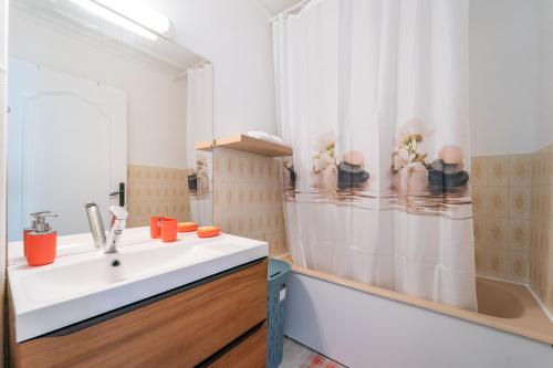 ein Bad mit einem Waschbecken und einem Duschvorhang in der Unterkunft Les 3 Lys - Bel appartement 3 Chambres in Sevran